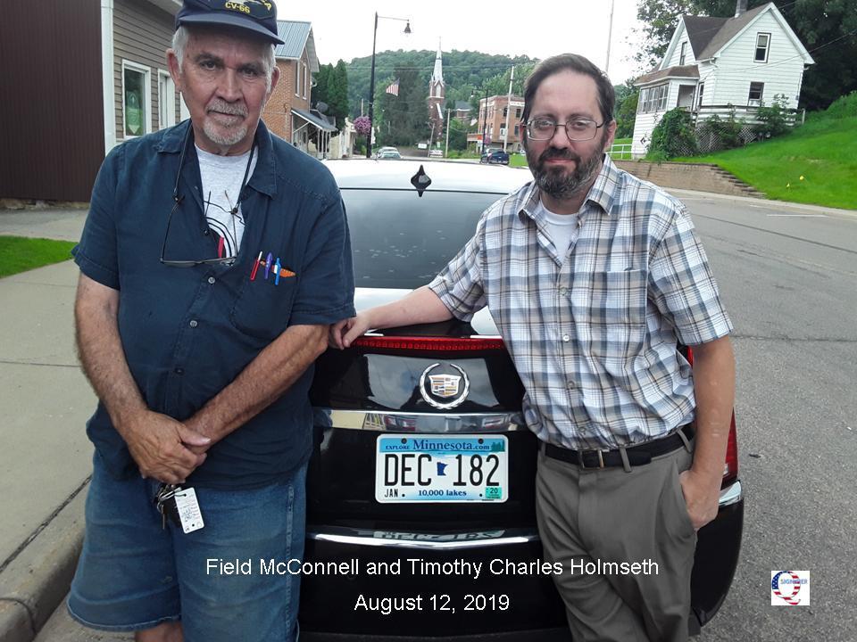 Two men standing next to a car.