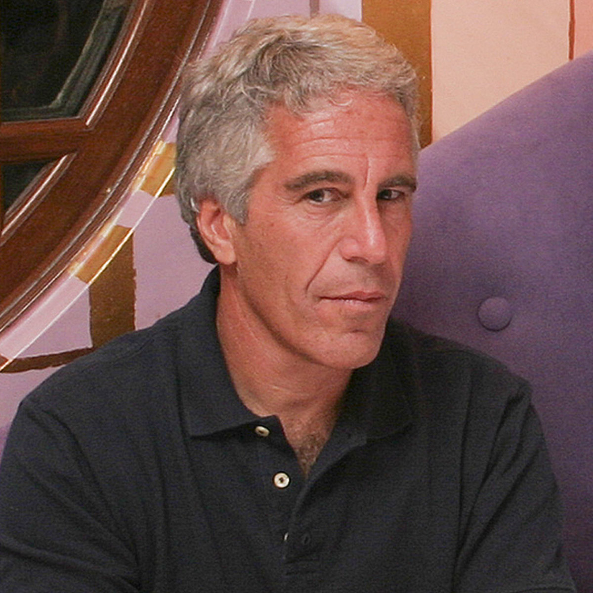 A man in a black shirt sitting on a purple chair.