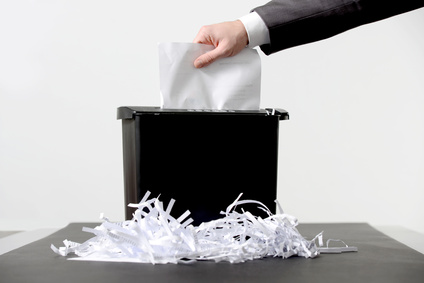 A man is putting shredded paper into a trash can.