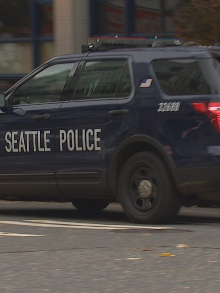 A seattle police car driving down the street.