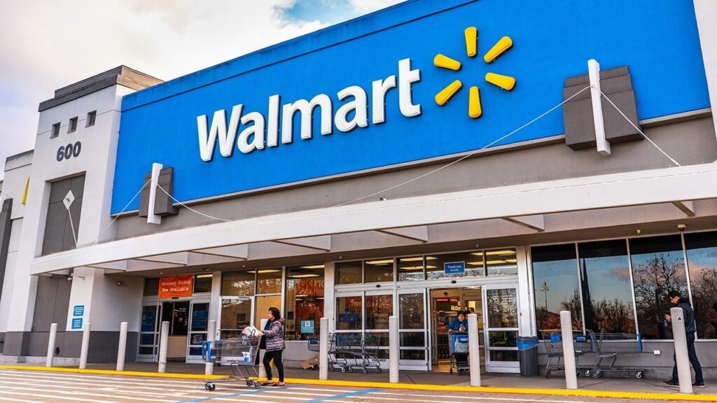 A picture of a walmart store with people walking in front of it.