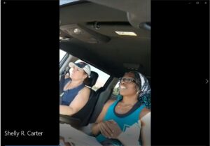 Two women in a car talking to each other.