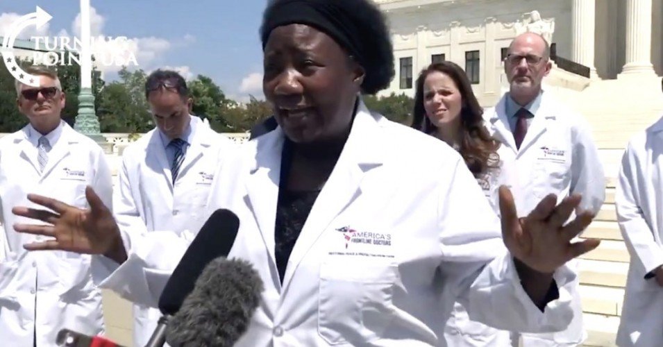 A group of women in lab coats standing in front of the supreme court.
