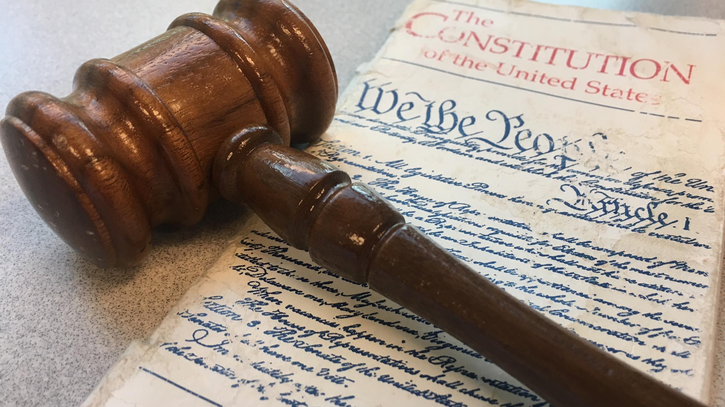 A gavel sits on top of the constitution of the united states.