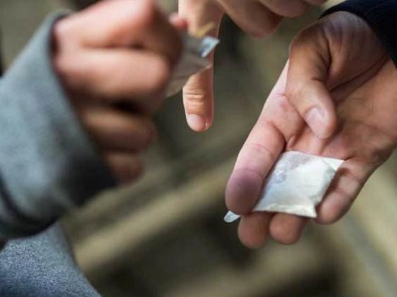 A person is holding a piece of a bag of drugs.