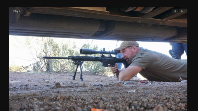 man in prone position wielding a sniper rifle