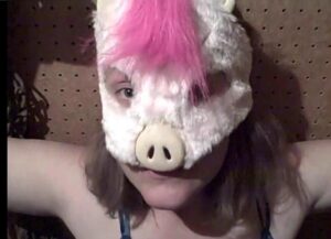 A woman wearing a stuffed unicorn mask.