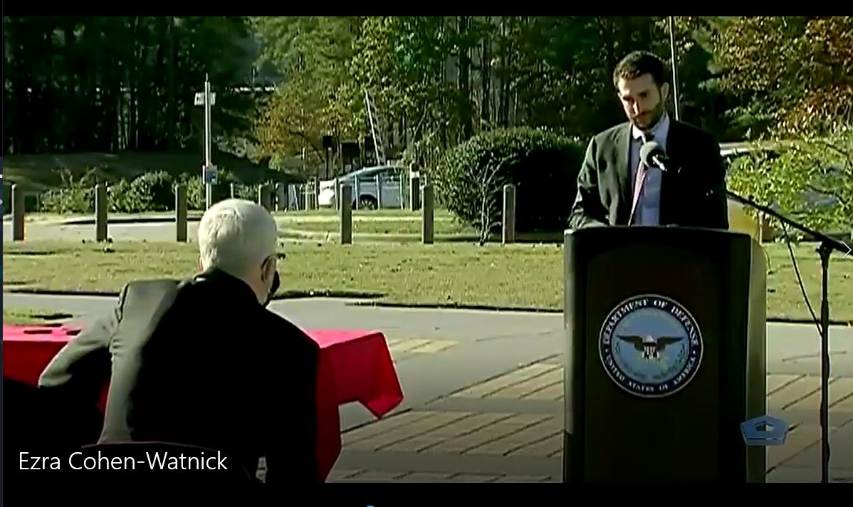 A man is speaking at a podium in front of a group of people.