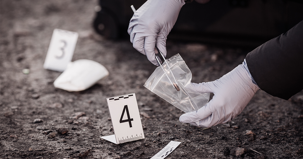 A person in gloves is putting a piece of paper on the ground.