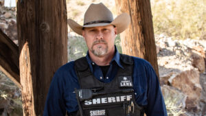 A man wearing a cowboy hat and sheriff's vest.