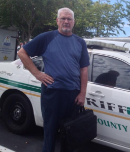 A man standing next to a police car.