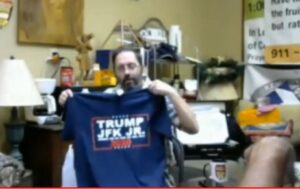A man is holding up a t-shirt with trump on it.