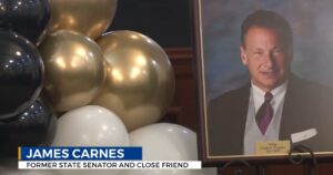 Jaes carnes image kept on a table near balloons