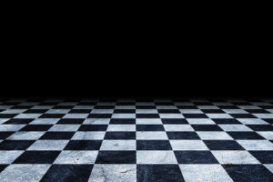 A black and white chess board on a dark floor.