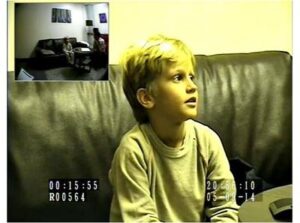 A young boy is sitting on a couch with a camera in front of him.