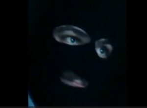 A man in a black mask with blue eyes.