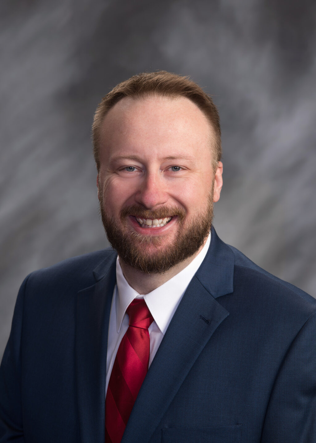 A man in a suit and tie smiling for the camera.