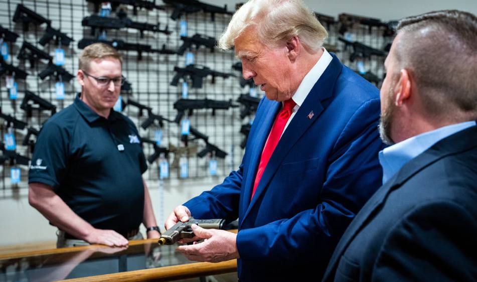 Donald trump looks at a gun in a gun store.
