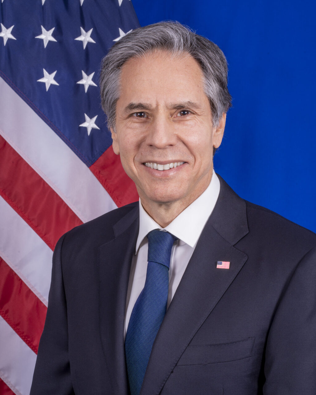 A man in a suit and tie standing in front of an american flag.