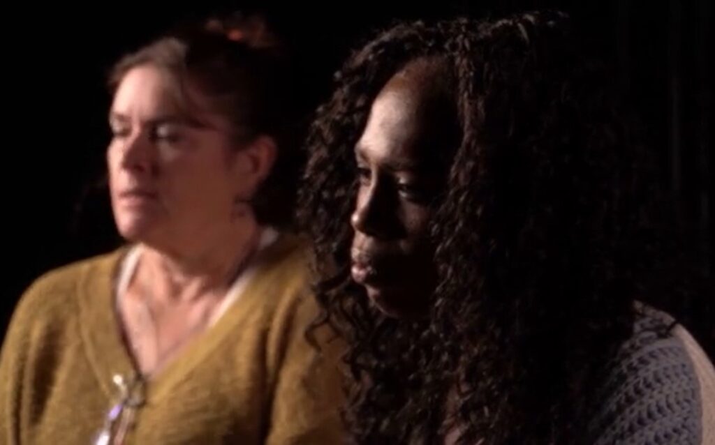 Two women sitting next to each other in a dark room.