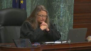 A woman sitting in a courtroom with a laptop on her lap.