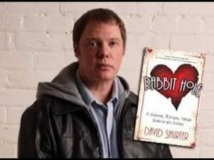 A man is standing next to a book with a heart on it.