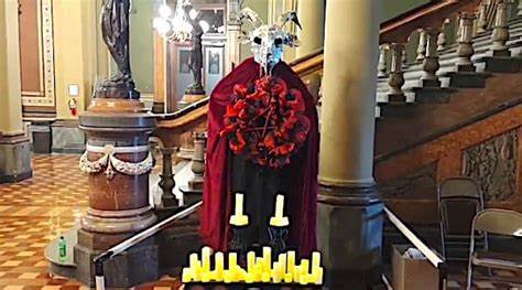 A statue of a devil with candles in front of a staircase.
