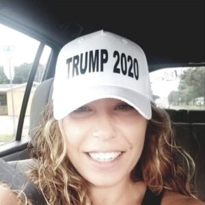 A woman in a car wearing a trump 2020 hat.
