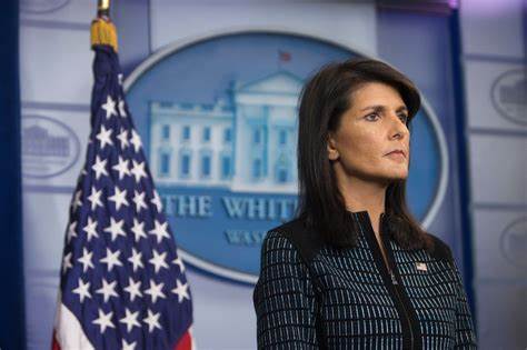 A woman standing in front of an american flag.